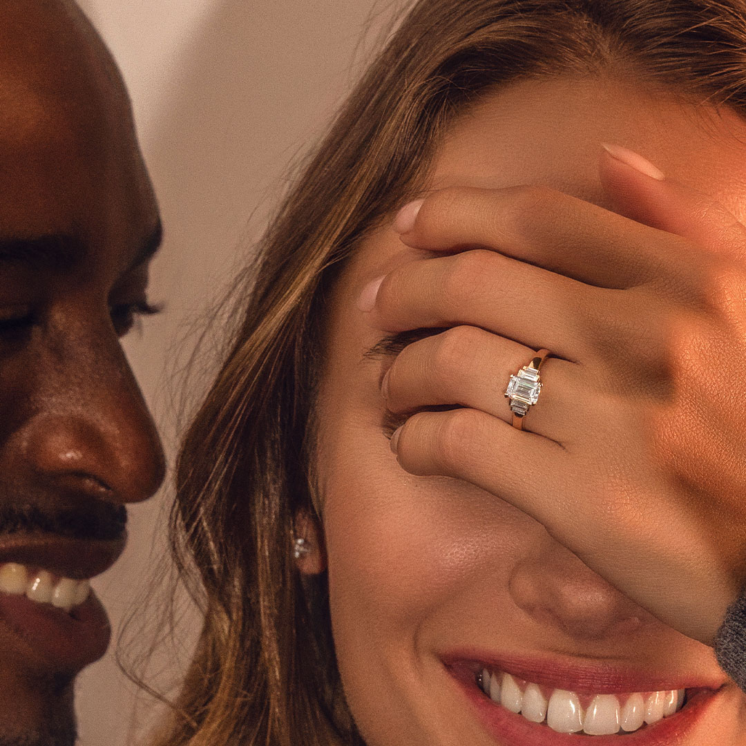 Couple avec une bague de fiançailles épaulée modèle Art Déco avec un diamant taille Émeraude de la Maison Amantys